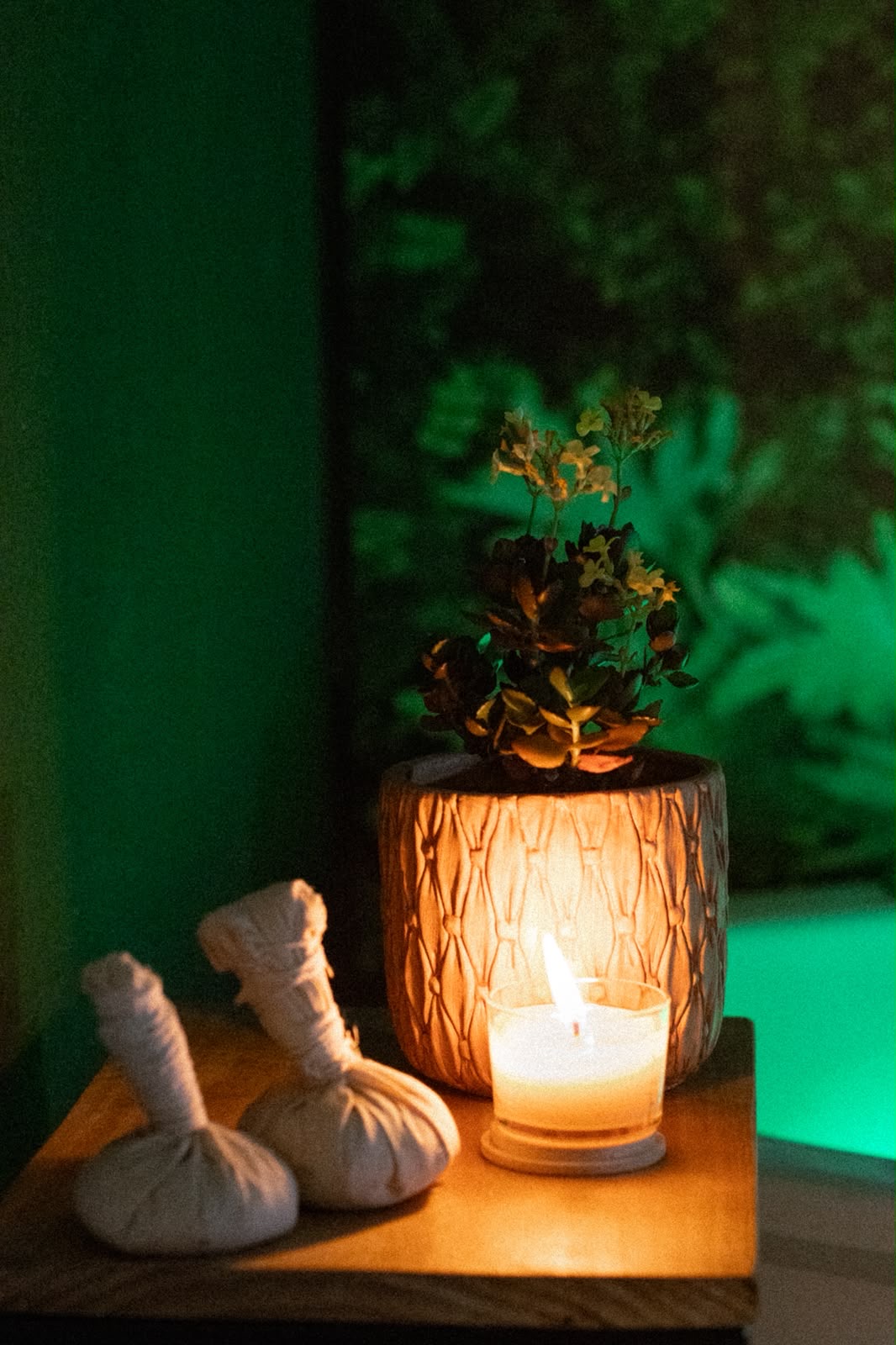 Pindas terapêuticas e vela acesa em ambiente com luz verde no Ápice Spa